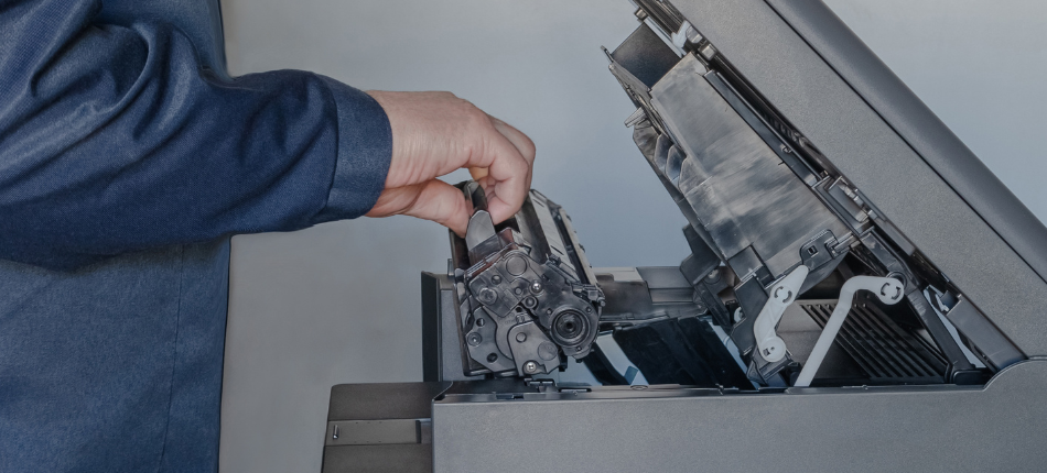 A person performing maintenance on an office printer, showcasing the importance of office printer service for ensuring optimal printer performance.