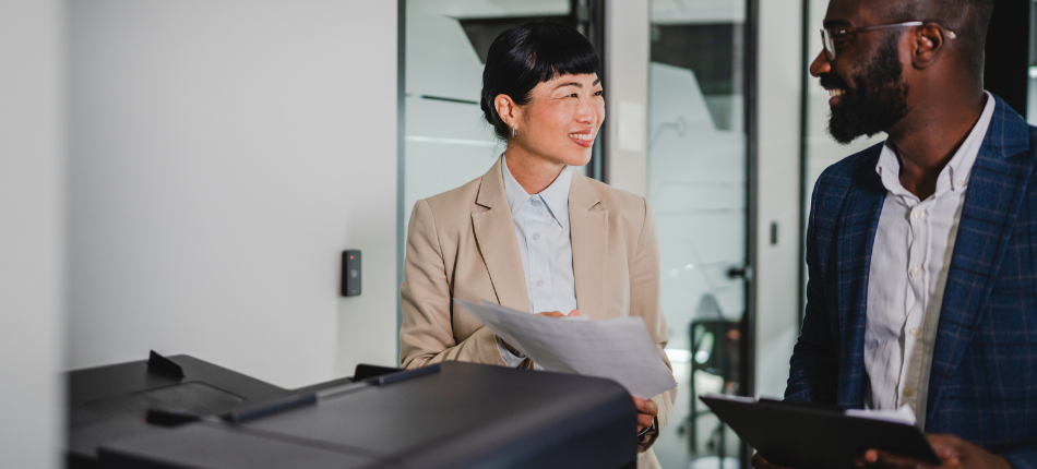 Two coworkers stand at their office printer as a conceptual image of managed print services.